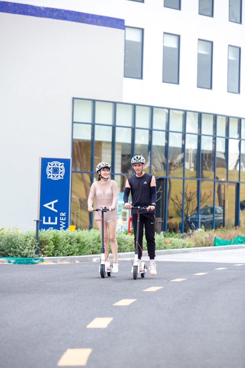 A couple riding electric scooters past the Sea Tower