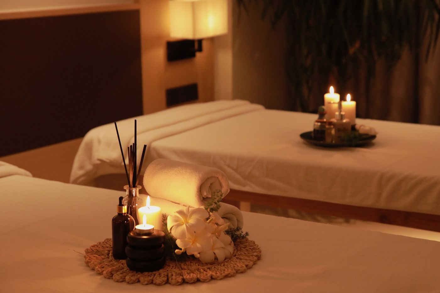 Spa treatment bed with rolled towels, candles and frangipani flowers